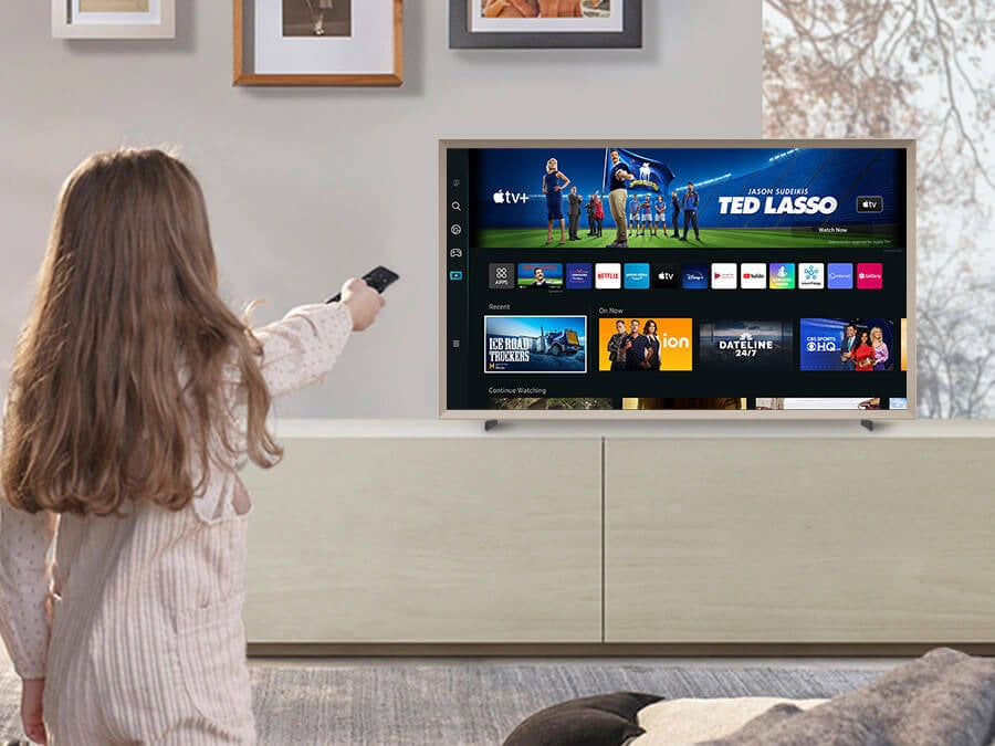 Person using a remote control to change channels on a smart TV displaying various apps and shows.