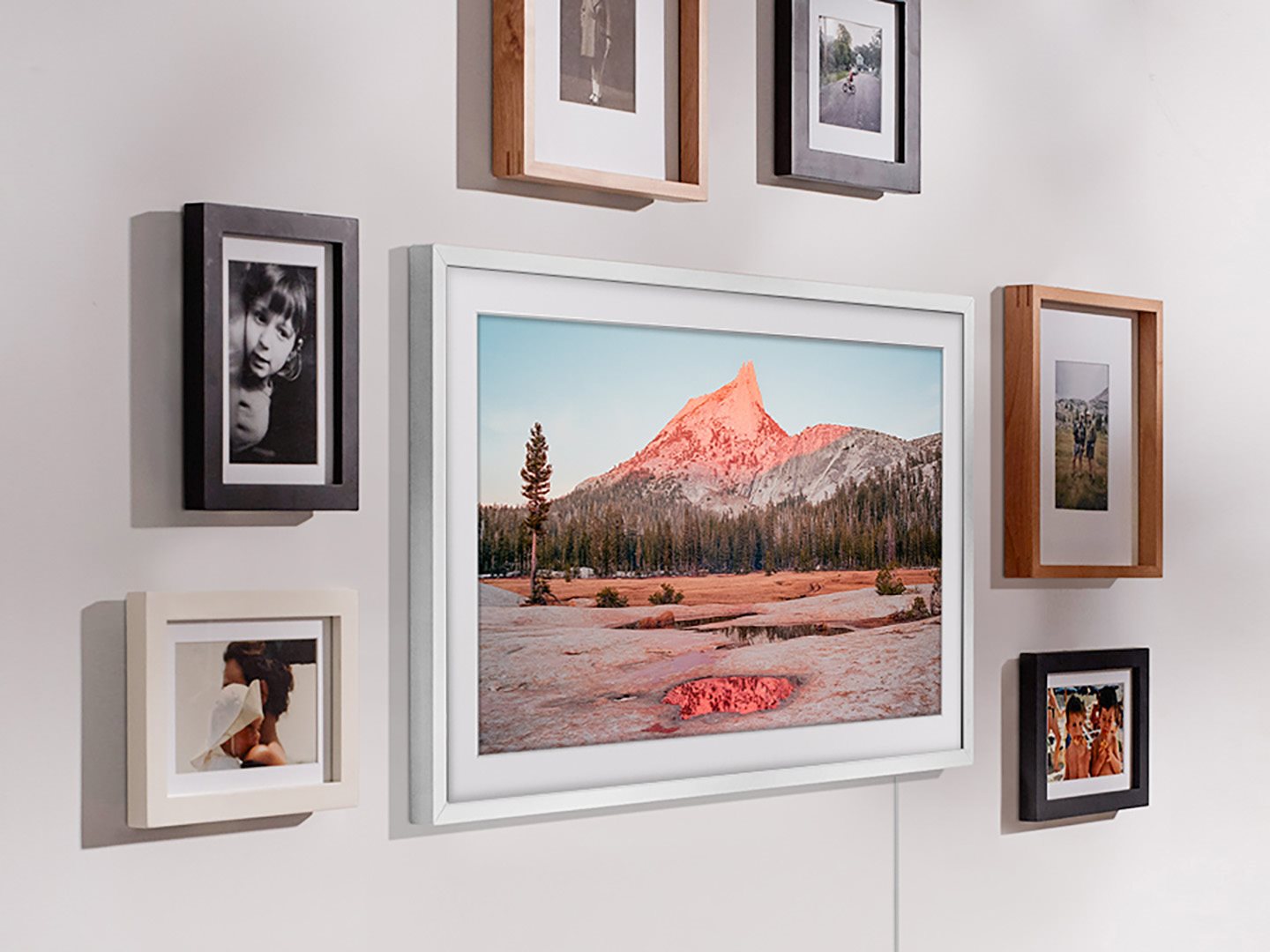 A white wall with various picture frames displayed of various colors.