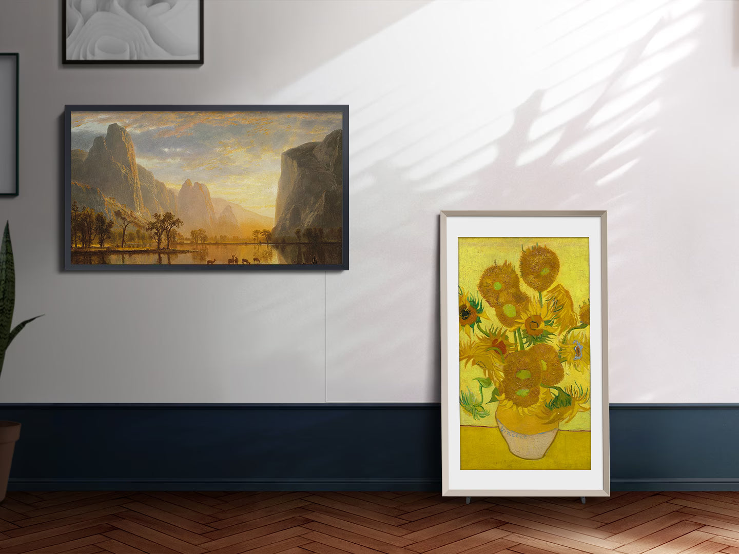 Framed artwork of sunflowers on a wall with another painting of a mountain landscape.